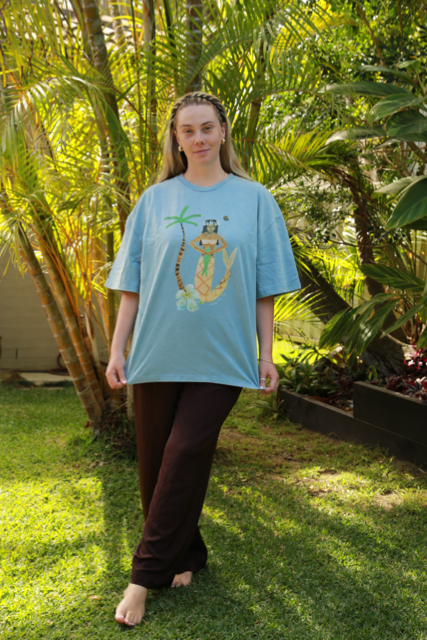 Person wearing a light blue t-shirt with a mermaid graphic design in a garden setting
