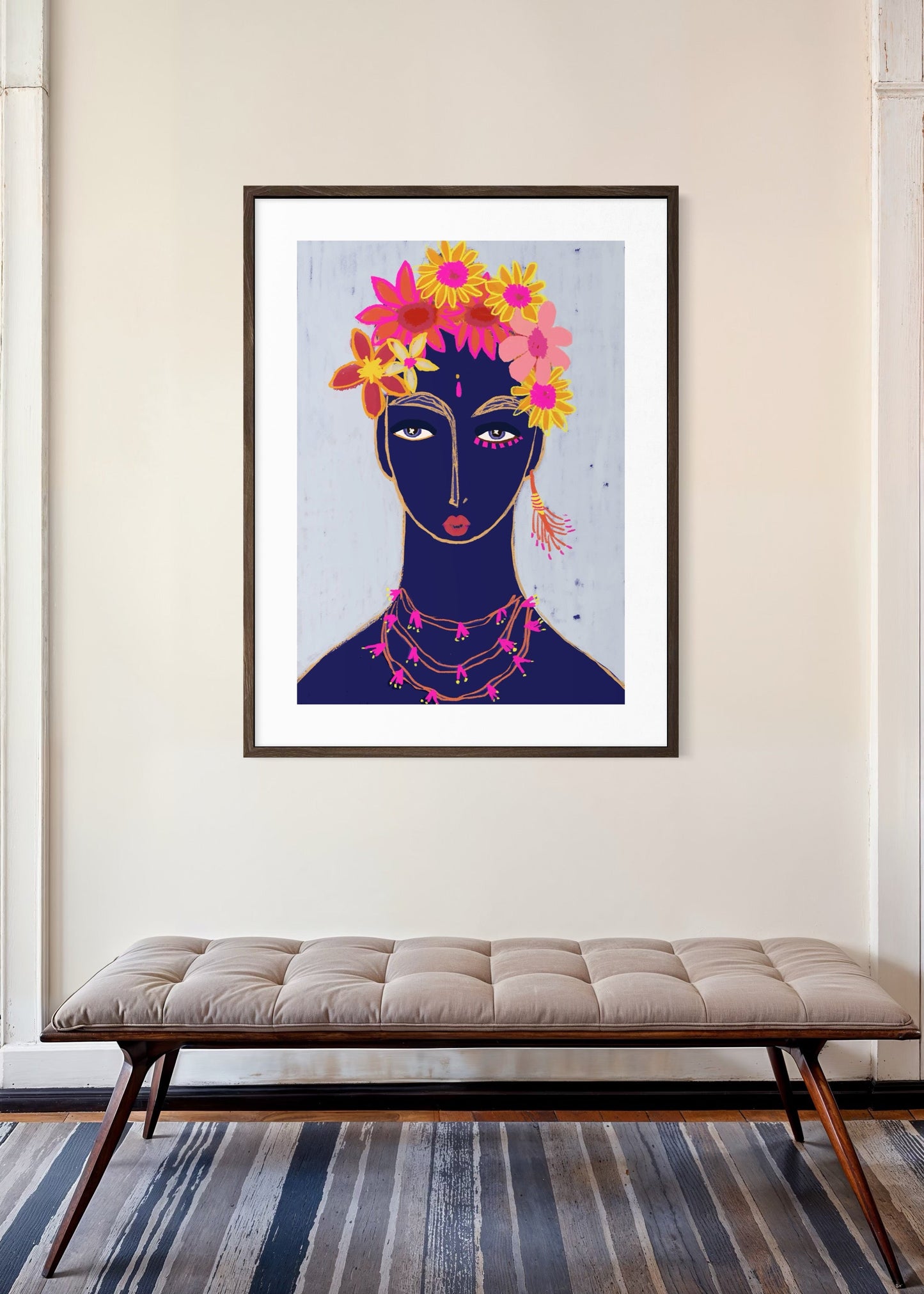 Framed artwork of a stylized woman with flowers on her head in a room with a bench and striped rug.