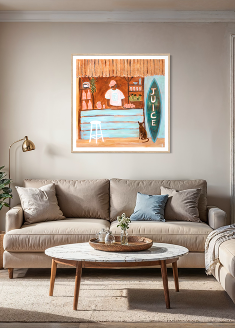 A framed art print depicting a beach bar scene with a surfer and the word 'JUICE' in green, hanging on a beige wall above a modern gray sofa in a styled living room.